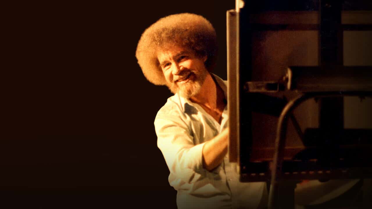 A photo of Bob Ross seated behind his easel.